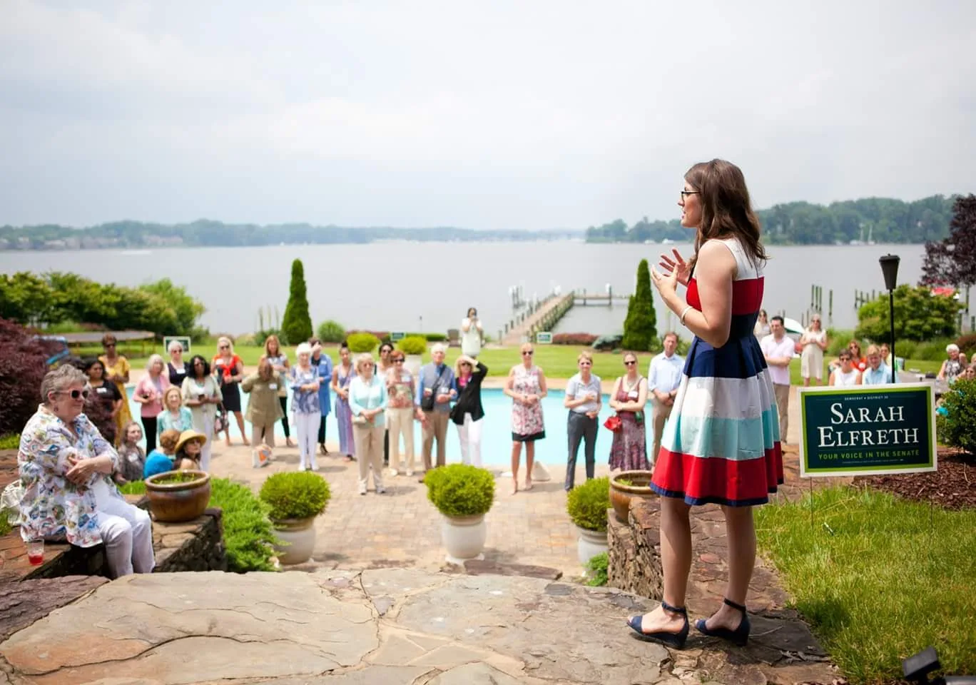 A speaker at a waterside garden event addressing supporters of a campaign.