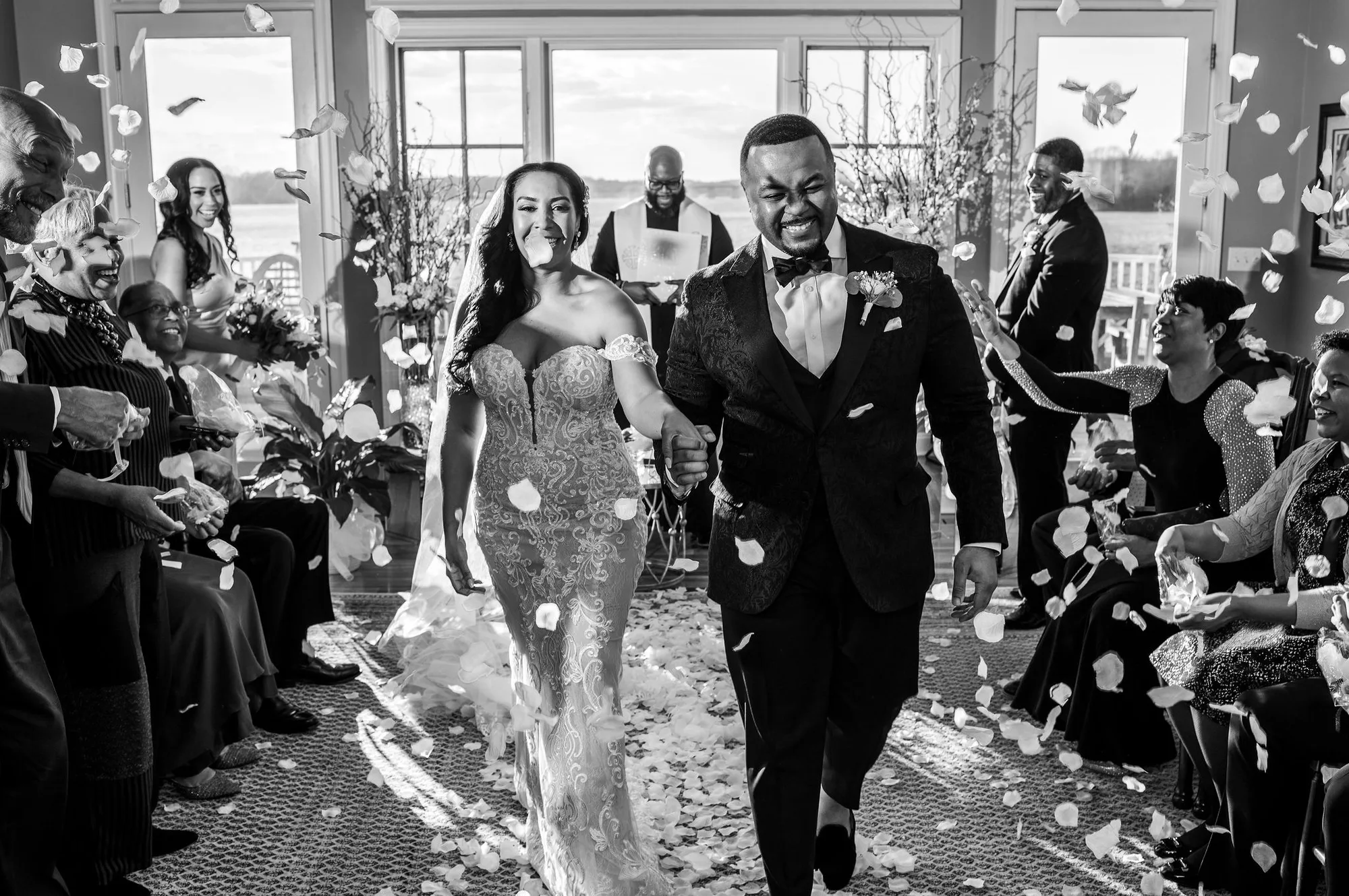 A bride and groom walking out of their ceremony through a shower of petals.