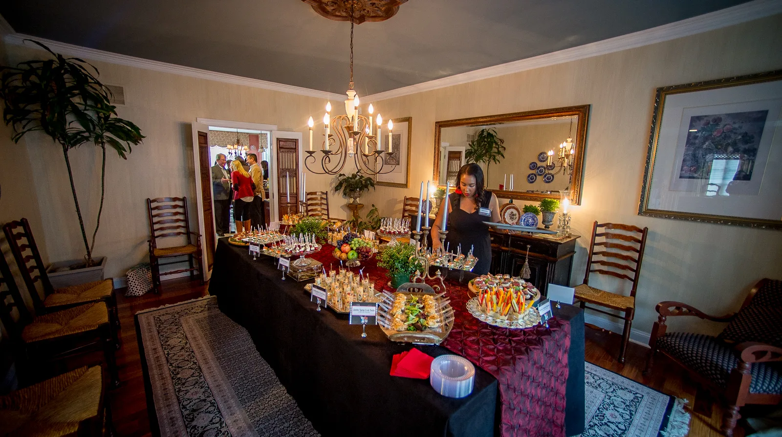 Melissa setting a long dining-room table with candles, tapas, and stems.